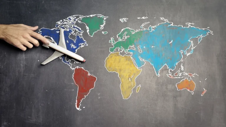 A hand moving a small model aeroplane across a chalk-drawn world map