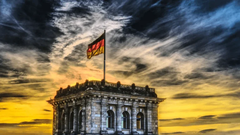 The German flag flying above the Reichstag building against a golden sunset