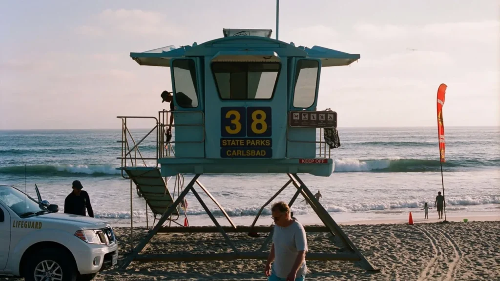 A lifeguard tower on a wide sandy beach with surf and an overcast sky