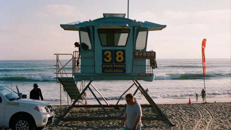A lifeguard tower on a wide sandy beach with surf and an overcast sky