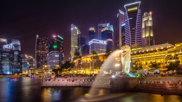 The Singapore skyline and Merlion fountain lit up at night across the water