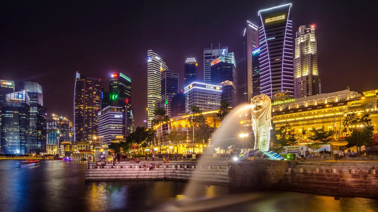 The Singapore skyline and Merlion fountain lit up at night across the water