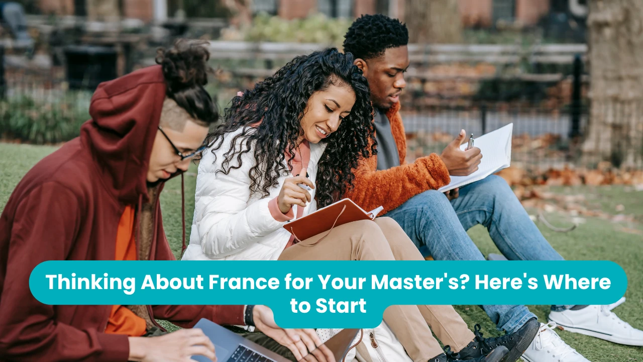 Banner reading 'Thinking About France for Your Master's? Here's Where to Start' across a photograph of three students sitting on grass in a city park with notebooks, a tablet and a laptop, autumn leaves and iron railings behind them