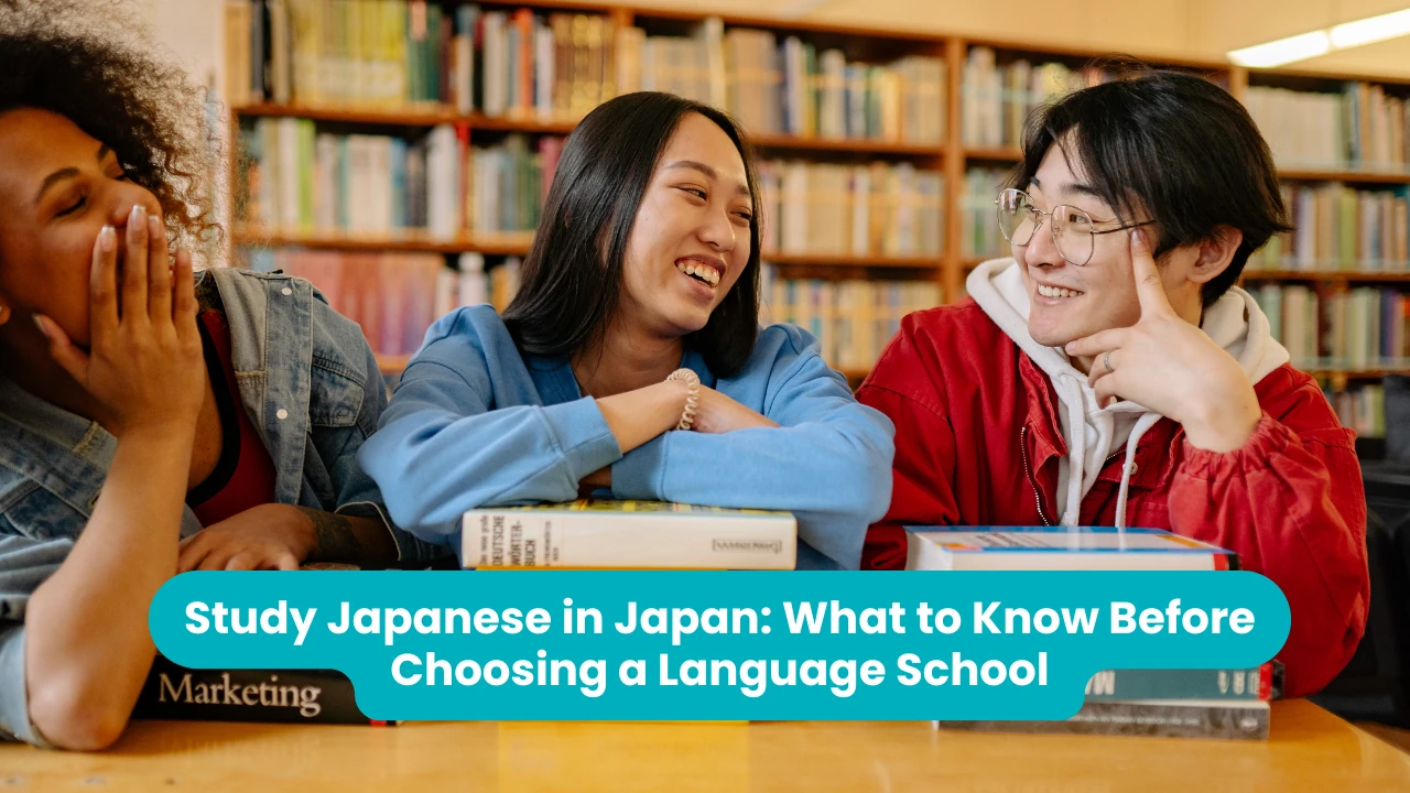 Study Japanese in Japan: What to Know Before Choosing a Language School — three students laughing together at a library table stacked with textbooks, tall bookshelves behind them