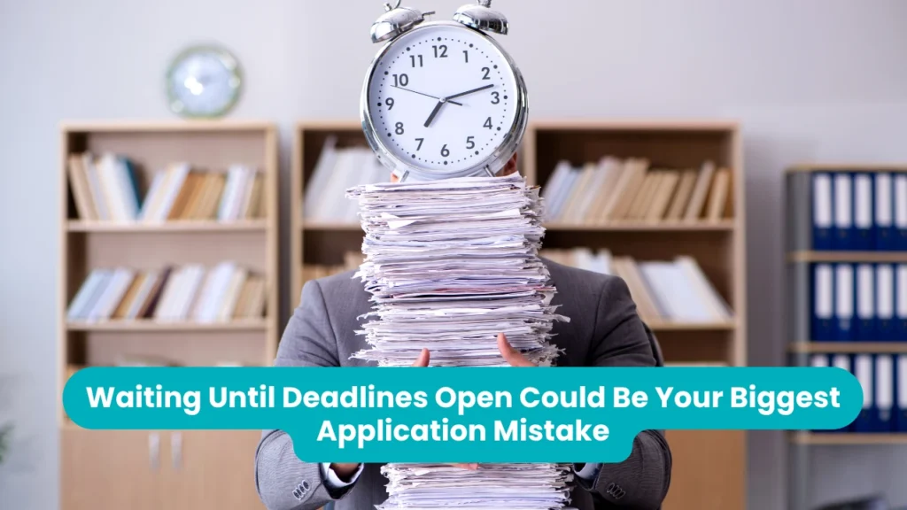 Banner reading 'Waiting Until Deadlines Open Could Be Your Biggest Application Mistake' across a photograph of a person in a grey suit standing in an office, holding a tall stack of paperwork that hides their face, with a large alarm clock balanced on top of the pile