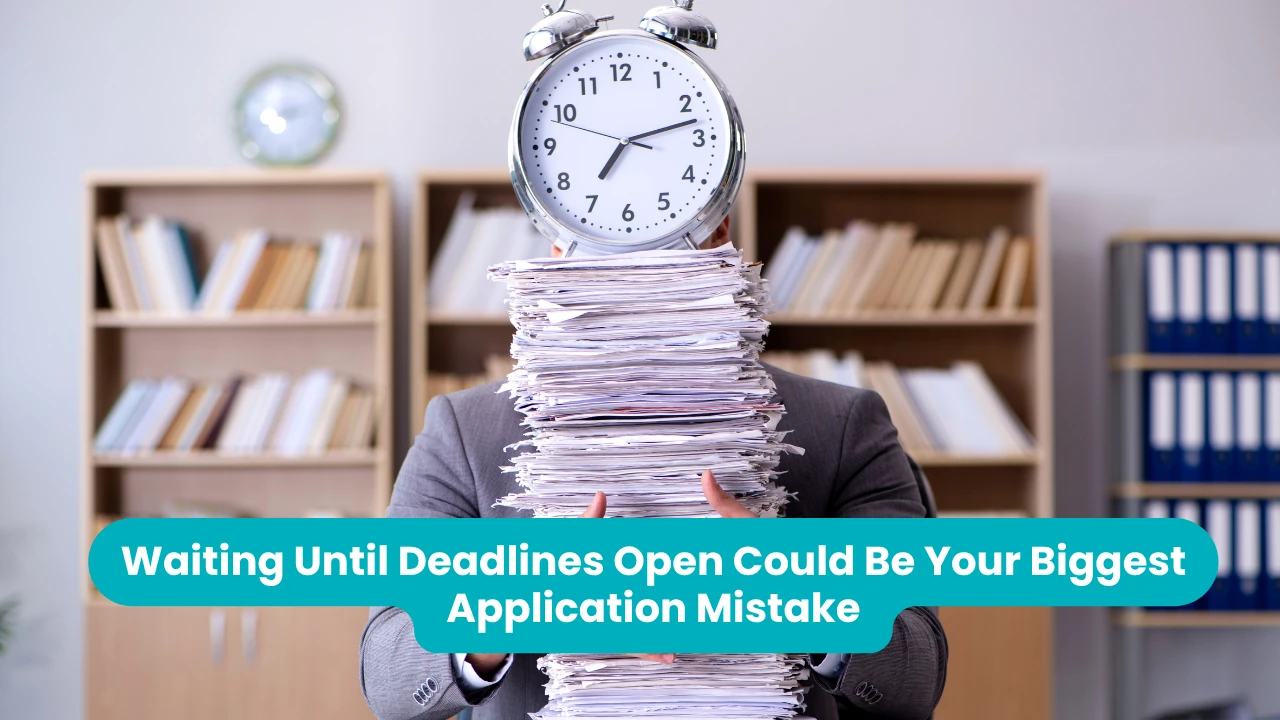 Banner reading 'Waiting Until Deadlines Open Could Be Your Biggest Application Mistake' across a photograph of a person in a grey suit standing in an office, holding a tall stack of paperwork that hides their face, with a large alarm clock balanced on top of the pile