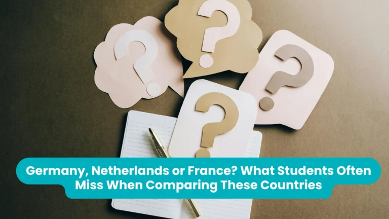 Banner reading 'Germany, Netherlands or France? What Students Often Miss When Comparing These Countries' across a photograph of four paper cut-out speech bubbles in cream and brown, each holding a question mark, arranged on a brown desk beside an open notebook and a gold pen